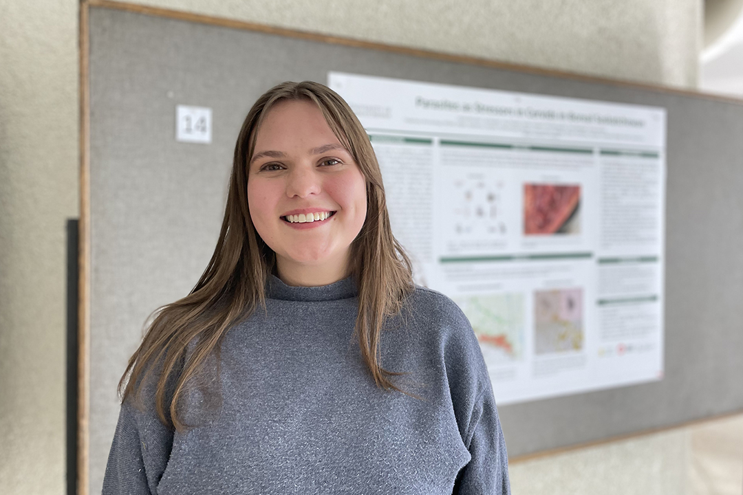 Graduate student standing in front of a research poster