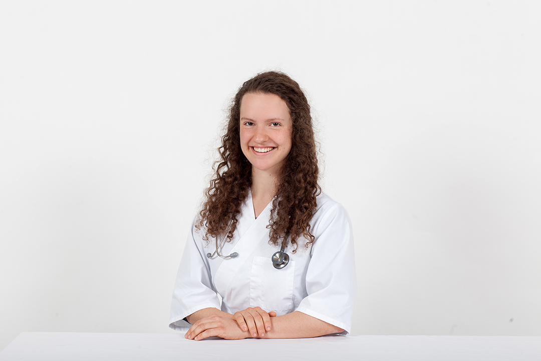 Vet student sitting with white background.