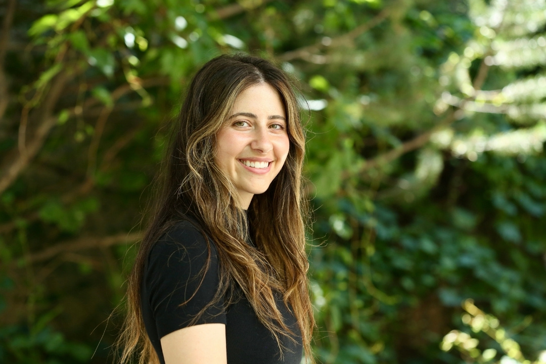Dr. Shayna Levitt in a black shirt with a leafy green background.